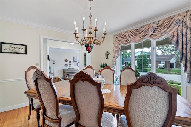dining area featuring baseboards, ornamental molding, light wood finished floors, and a notable chandelier