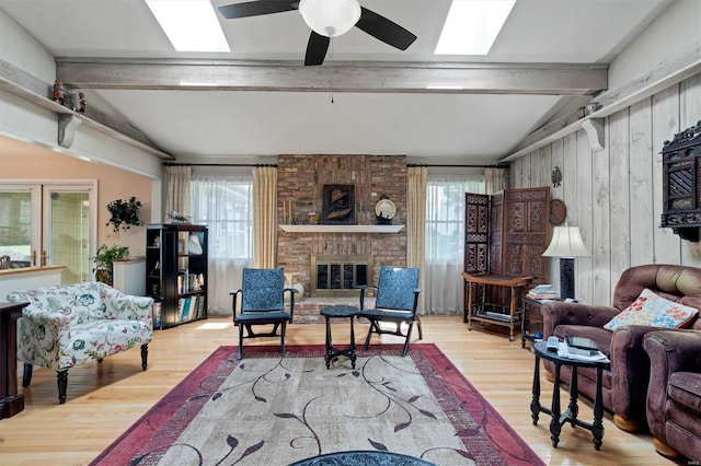 living room with a brick fireplace, lofted ceiling with skylight, wood finished floors, and a healthy amount of sunlight