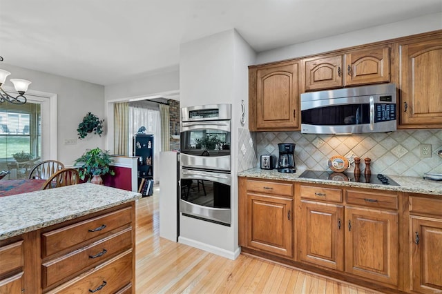 kitchen featuring stainless steel appliances, light stone counters, plenty of natural light, and light wood finished floors