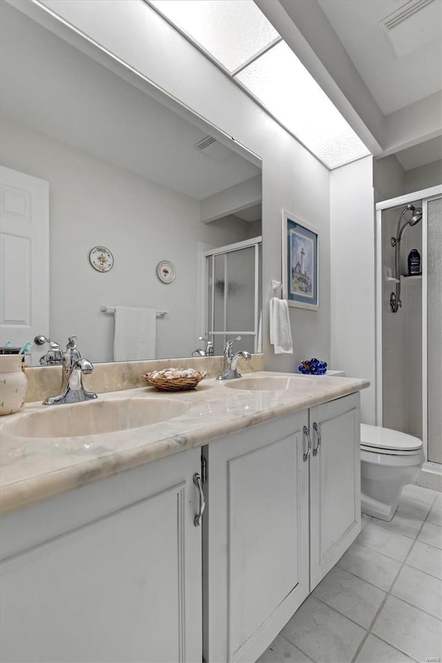 bathroom featuring a sink, a shower stall, toilet, and double vanity