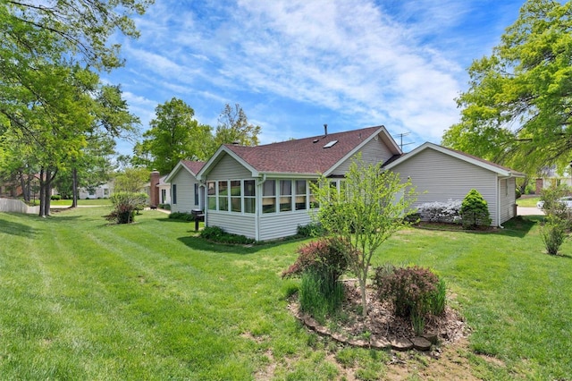 view of home's exterior with a lawn, a shingled roof, and a sunroom