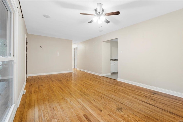 empty room featuring ceiling fan, baseboards, and light wood-type flooring