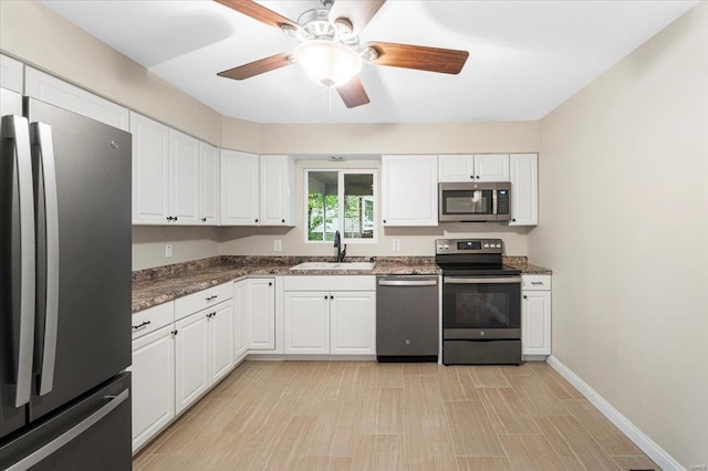 kitchen featuring a sink, appliances with stainless steel finishes, baseboards, and white cabinetry