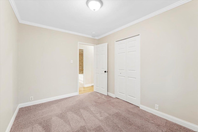 unfurnished bedroom featuring crown molding, carpet, baseboards, and a closet