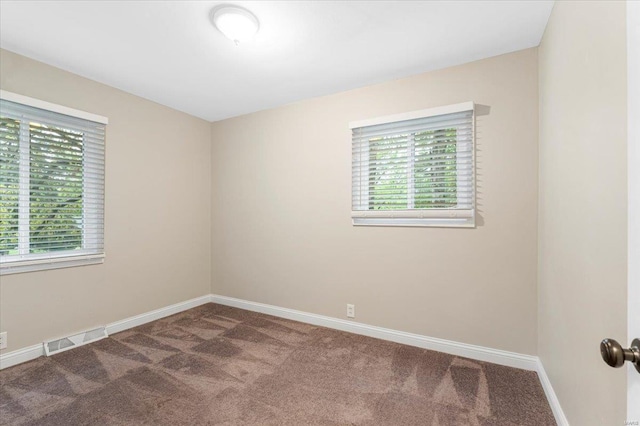 carpeted empty room featuring baseboards, visible vents, and a healthy amount of sunlight