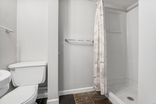 bathroom featuring baseboards, a stall shower, toilet, and stone finish flooring
