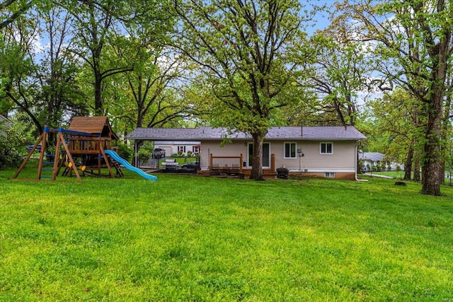 back of house featuring a lawn, a playground, and a wooden deck