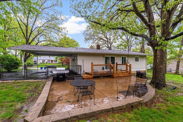 back of property featuring a chimney, an attached carport, fence, and a deck