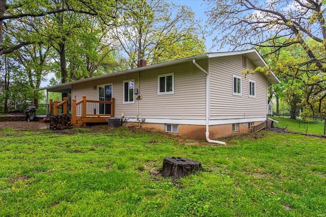 back of house with fence, a deck, a chimney, central air condition unit, and a yard