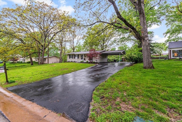ranch-style home featuring driveway, a front lawn, and a carport