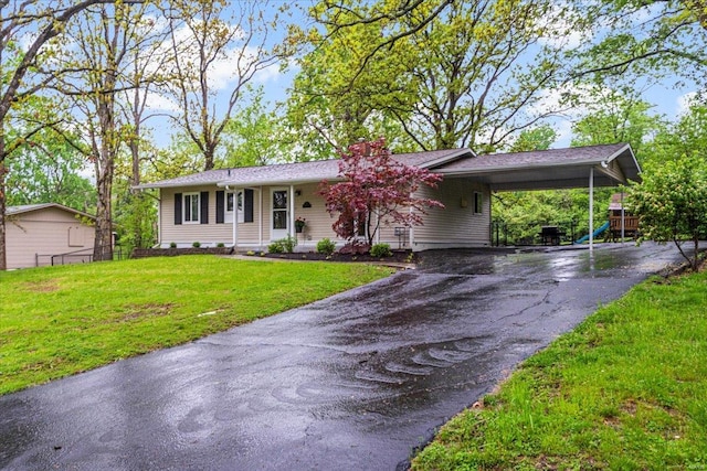 ranch-style house featuring fence, a front lawn, an attached carport, a chimney, and driveway