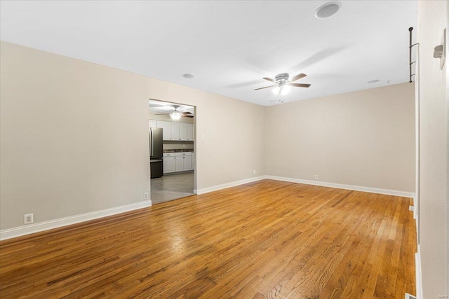 unfurnished room featuring baseboards, a ceiling fan, and light wood finished floors