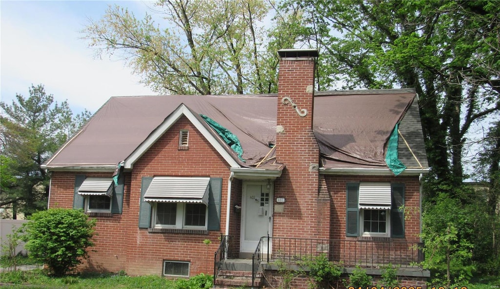 view of front of property with a chimney and brick siding