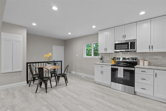 kitchen featuring backsplash, stainless steel appliances, baseboards, and white cabinetry