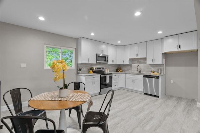 kitchen with a sink, stainless steel appliances, recessed lighting, white cabinetry, and decorative backsplash