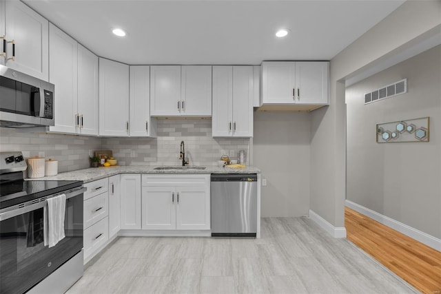 kitchen featuring visible vents, baseboards, a sink, appliances with stainless steel finishes, and backsplash