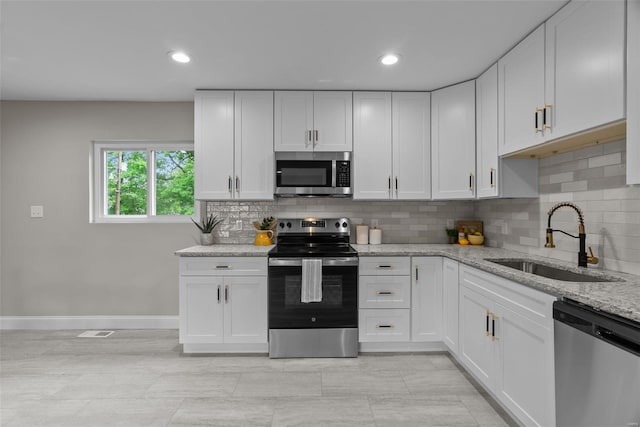 kitchen with baseboards, a sink, white cabinets, and stainless steel appliances
