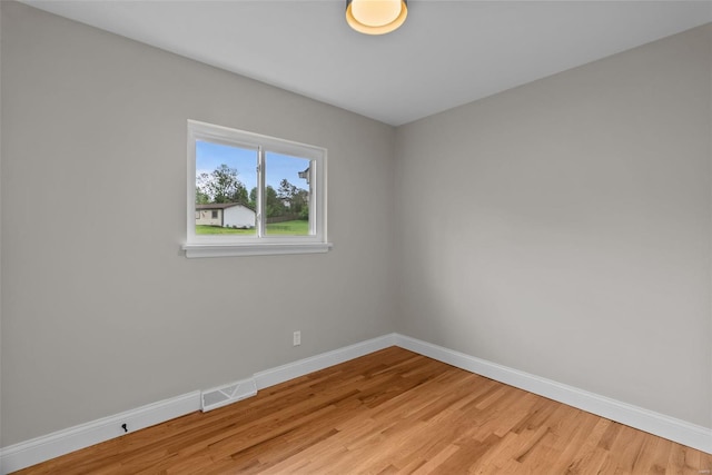 spare room with baseboards, light wood-type flooring, and visible vents