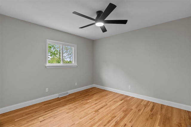 empty room featuring visible vents, a ceiling fan, baseboards, and wood finished floors