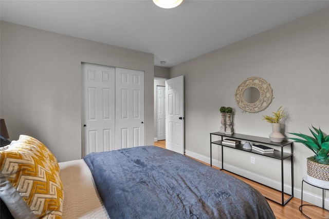 bedroom featuring baseboards, wood finished floors, and a closet