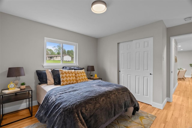 bedroom featuring a closet, baseboards, and light wood-style floors