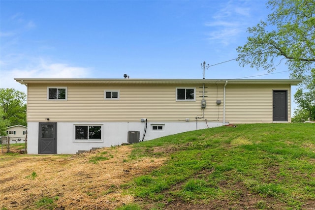 rear view of house featuring central air condition unit and a yard