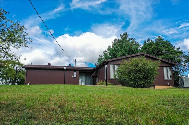 rear view of property featuring central air condition unit and a yard