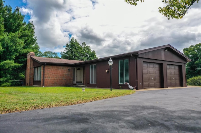 ranch-style home with driveway, a chimney, a front yard, brick siding, and an attached garage