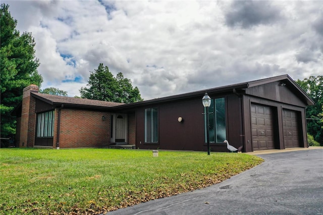 single story home with a chimney, a front yard, brick siding, aphalt driveway, and an attached garage