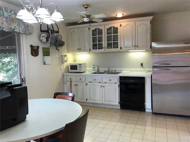 kitchen with a sink, dishwasher, freestanding refrigerator, decorative backsplash, and white microwave