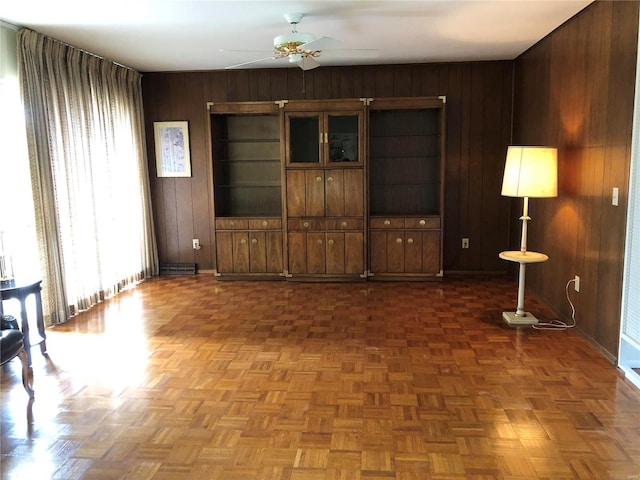 unfurnished room with baseboards, ceiling fan, and wooden walls