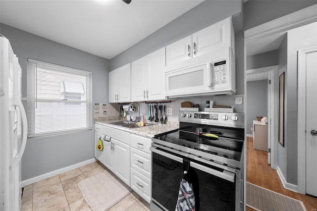 kitchen featuring baseboards, a sink, white cabinetry, and white appliances