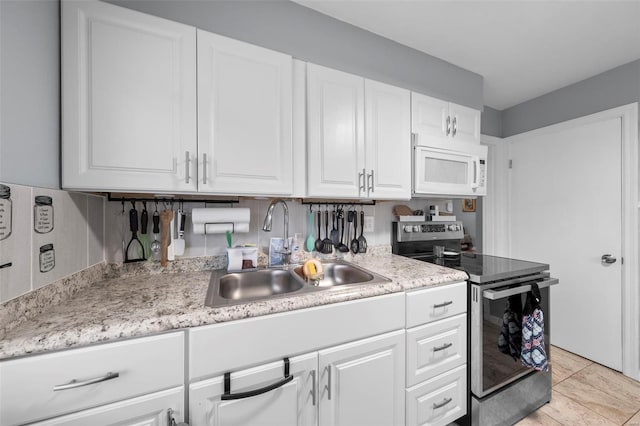 kitchen with a sink, white microwave, stainless steel range with electric cooktop, and light countertops