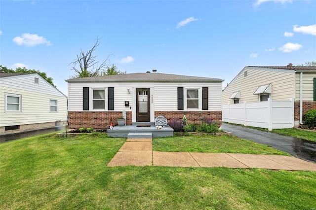 bungalow-style home featuring fence, a front yard, and brick siding