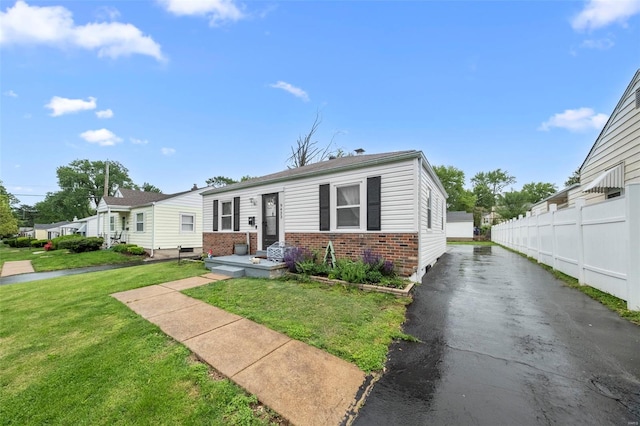 view of front of home with brick siding, a front lawn, and fence