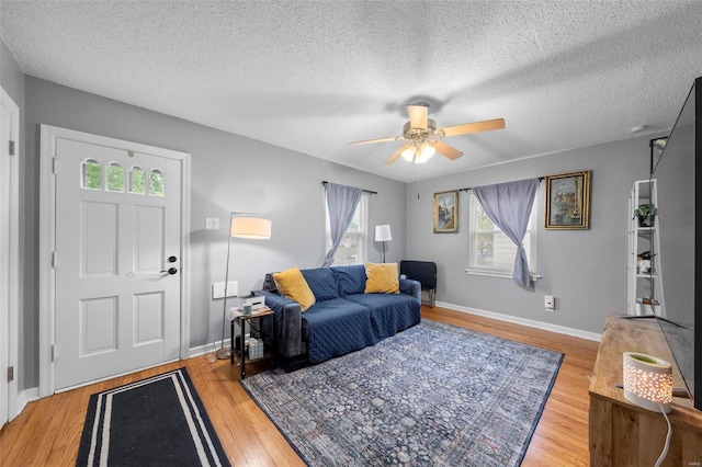 living area featuring a textured ceiling, ceiling fan, wood finished floors, and a wealth of natural light