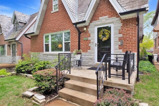 entrance to property featuring brick siding, fence, and stone siding