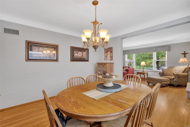 dining room featuring visible vents, baseboards, a notable chandelier, and light wood-type flooring