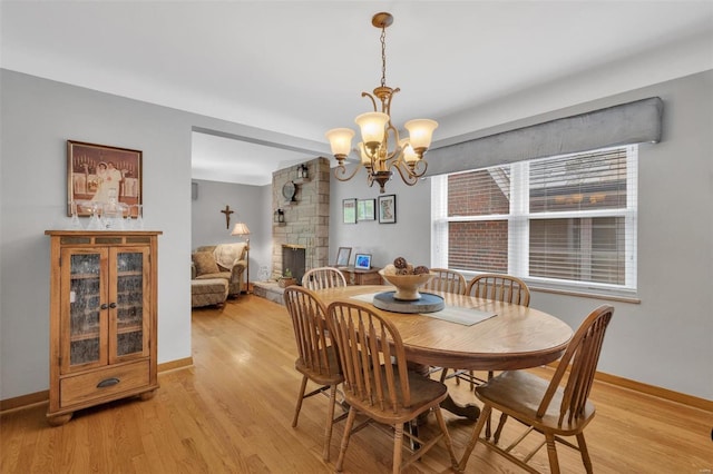 dining area with baseboards, a notable chandelier, and light wood-type flooring