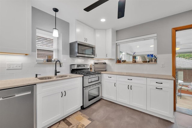 kitchen with a ceiling fan, tasteful backsplash, a sink, white cabinets, and stainless steel appliances