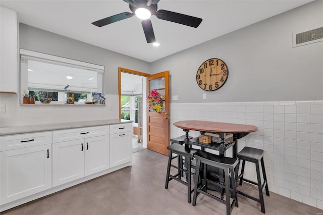 dining area with ceiling fan, visible vents, tile walls, a wainscoted wall, and recessed lighting