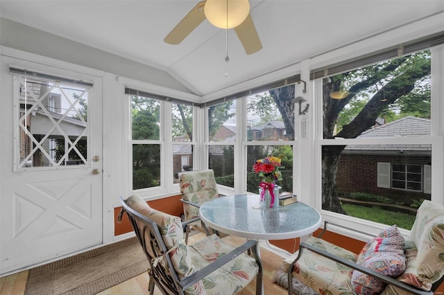 sunroom / solarium with vaulted ceiling, a healthy amount of sunlight, and wood finished floors