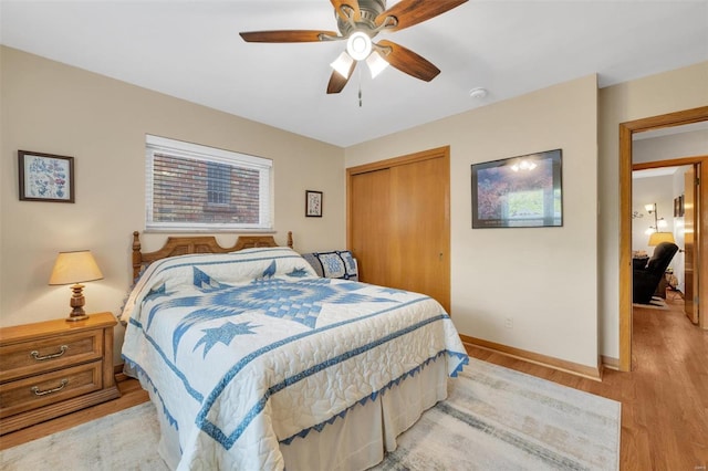 bedroom with light wood-style floors, ceiling fan, baseboards, and a closet