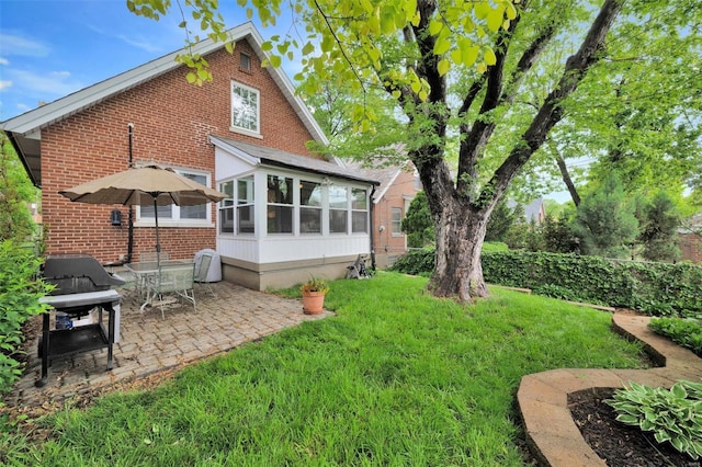 back of house with a sunroom, a patio area, a lawn, and brick siding