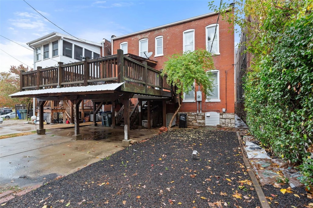 back of house featuring a wooden deck, stairs, and brick siding