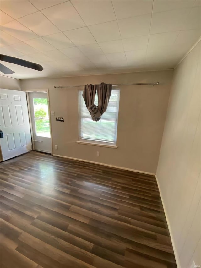 empty room with dark wood-style flooring, ceiling fan, and baseboards