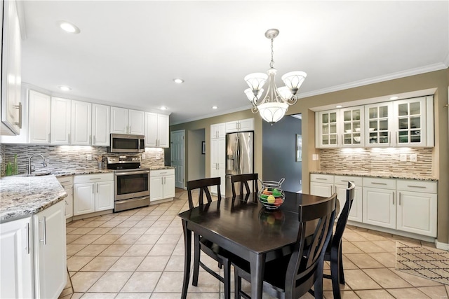 kitchen with stainless steel appliances, tasteful backsplash, light tile patterned flooring, a chandelier, and crown molding