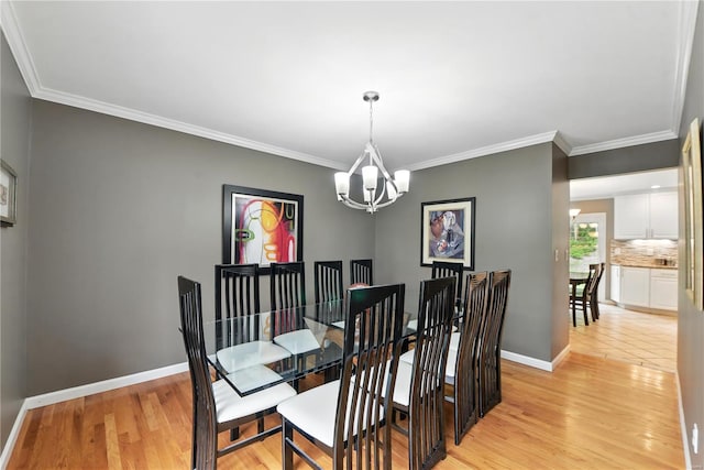 dining space with a chandelier, ornamental molding, light wood-style flooring, and baseboards