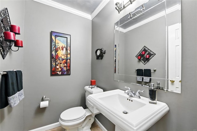 bathroom featuring crown molding, a sink, toilet, and baseboards