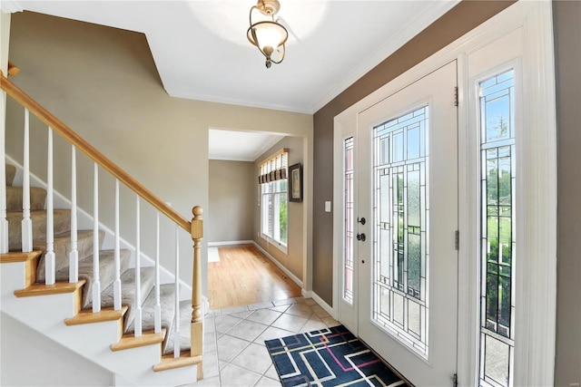 entryway featuring stairway, light tile patterned floors, crown molding, and baseboards